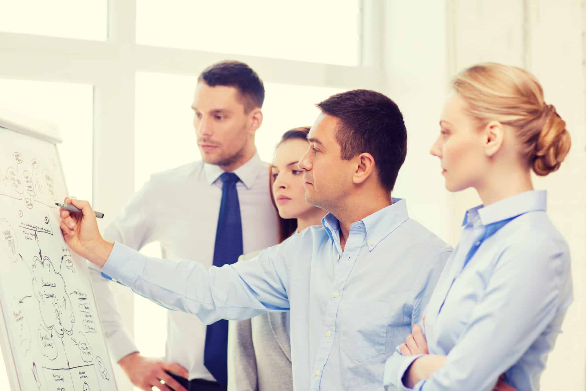 4 personnes discutant autour d'un tableau avec des chiffres au bureau